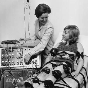 29th January 1968:  Paula Byrne demonstrates an electronic slimming device to actress Alison Frazer. Pads all over Alison's body stimulate her muscles with a mild electric current, with the same result as exercise.  (Photo by Keystone/Getty Images)