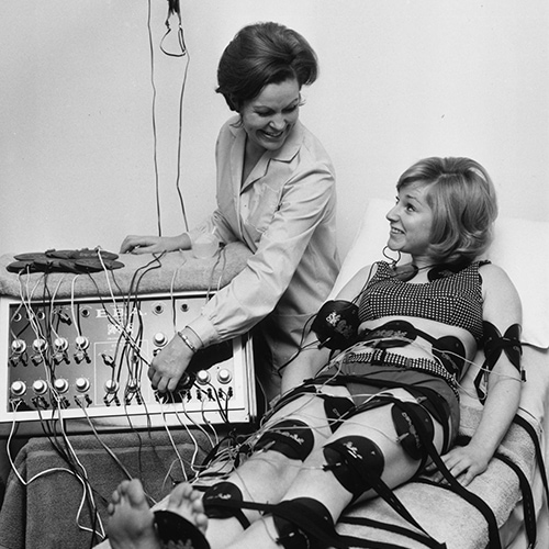29th January 1968:  Paula Byrne demonstrates an electronic slimming device to actress Alison Frazer. Pads all over Alison's body stimulate her muscles with a mild electric current, with the same result as exercise.  (Photo by Keystone/Getty Images)